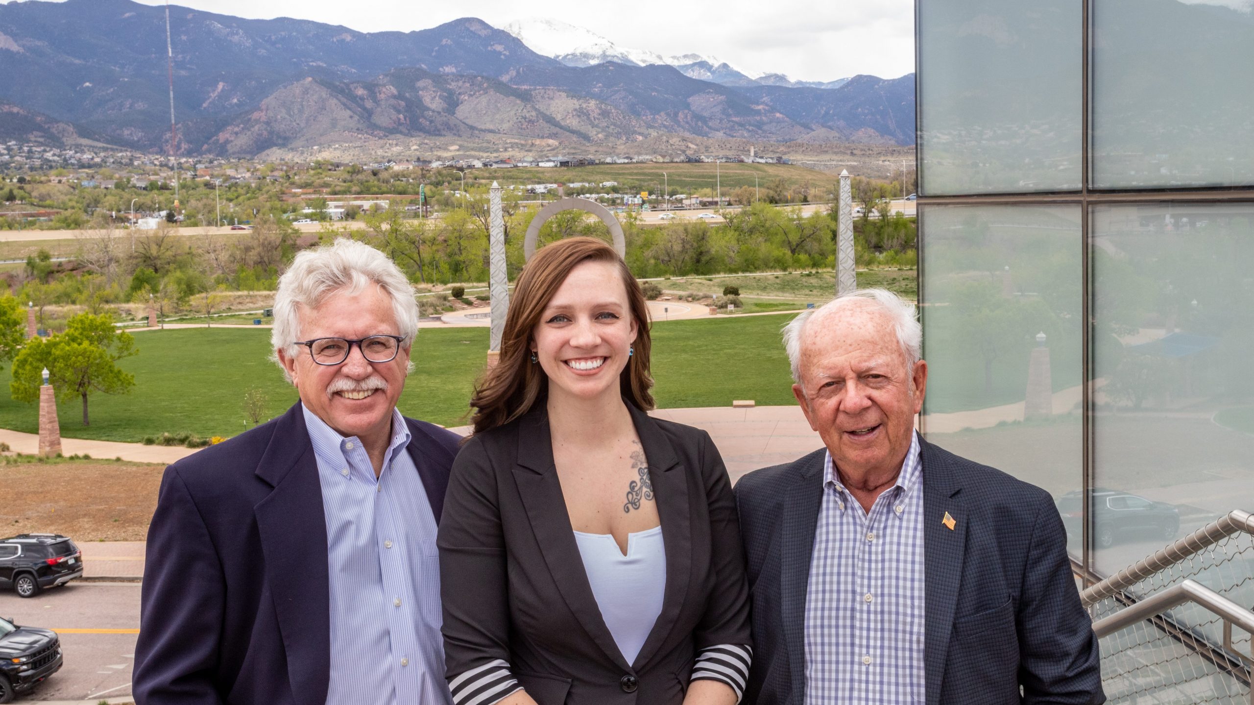 Kevin Walker, Rebecca Harris, and Terry Schooler with the front range, and America the Beautiful park behind them.